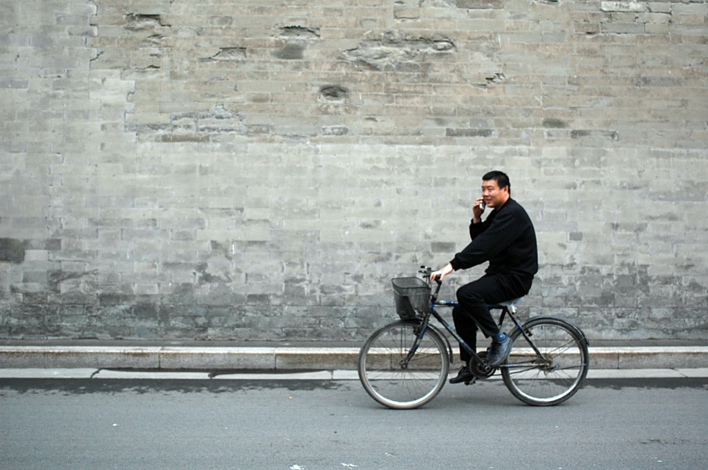 a chinese guy cycling and using his mobile