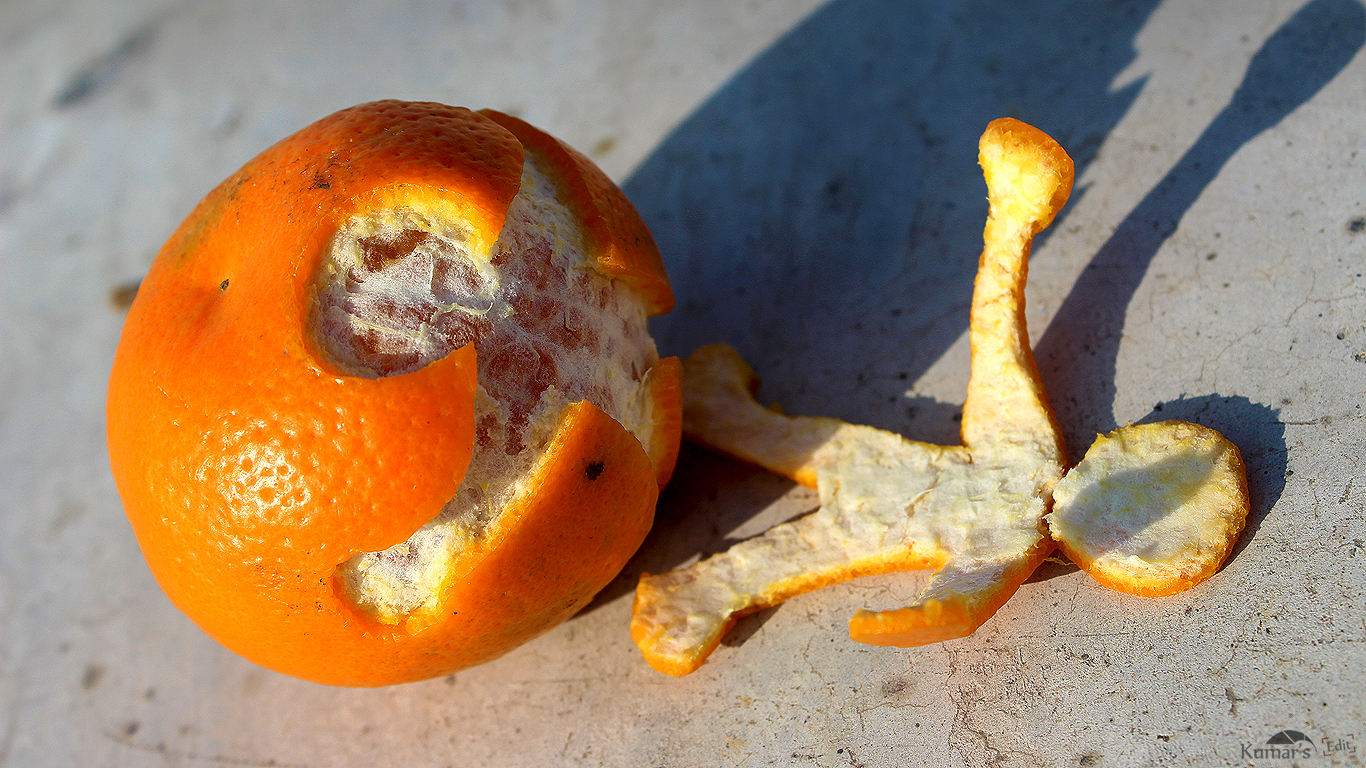 An orange with a shape of a person cut out. The cut out shape lies next to the orange.