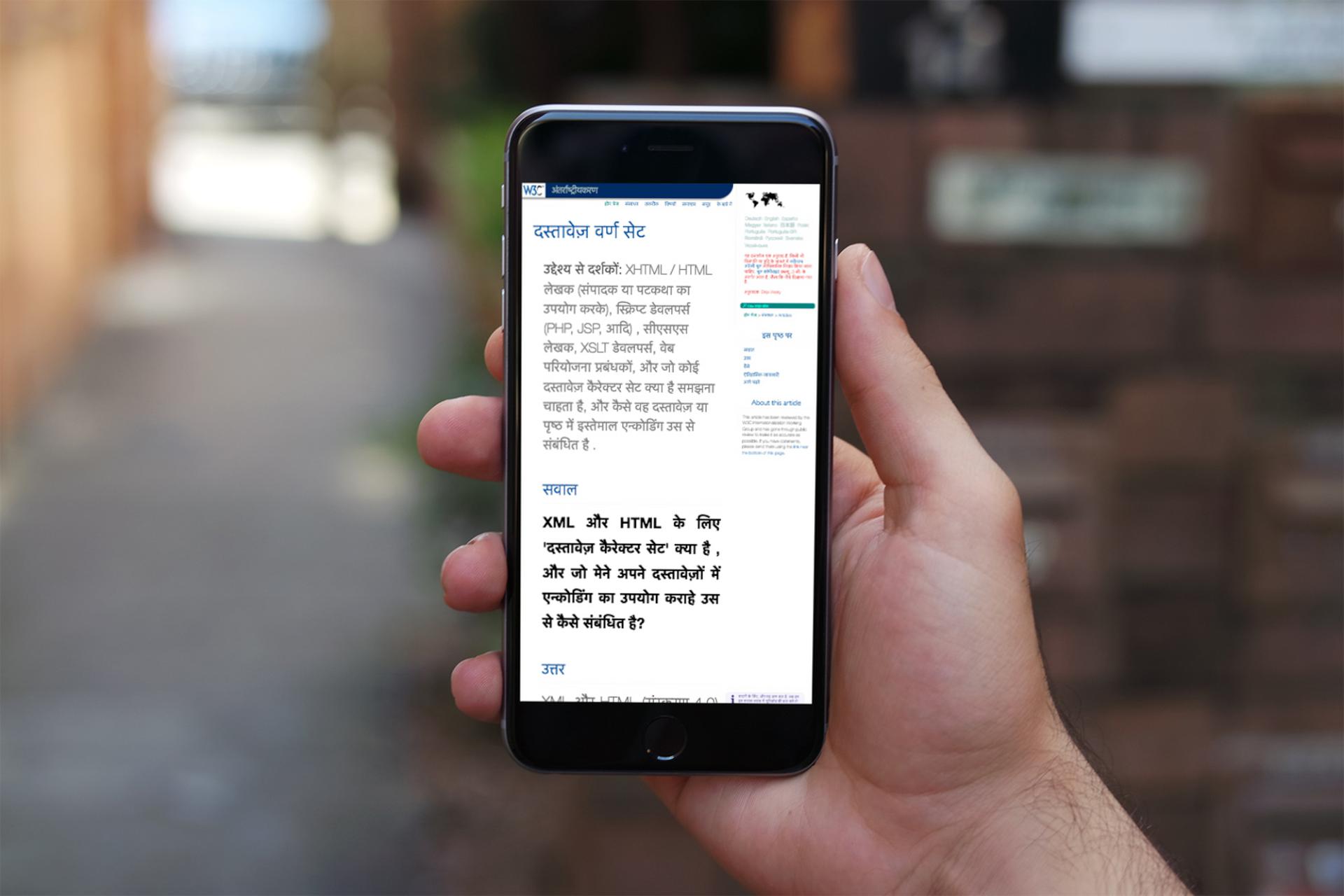 [Photo: A hand with a mobile phone that shows a page in Hindi from the W3C site]