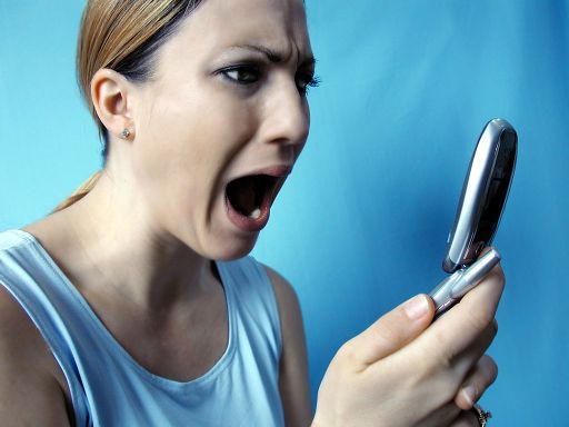 Photo d'une femme hurlant d'horreur face à son téléphone portable