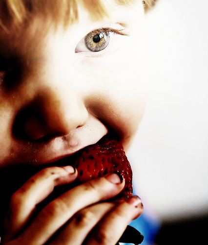 Child enjoying a strawberry.