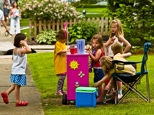 Several kids running a lemonade stand.