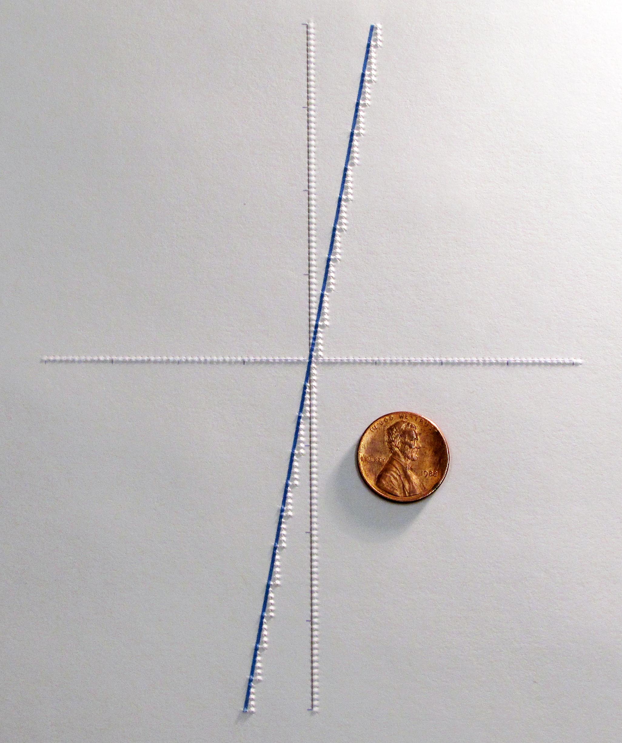 Photograph of a embossed tactile graphic, generated by the ViewPlus SpotDot printer.  Raised dots are evident, depicting the X and Y axis and a data line (overprinted in blue), traversing from the lower left to the upper right. A penny is shown for size comparison. 