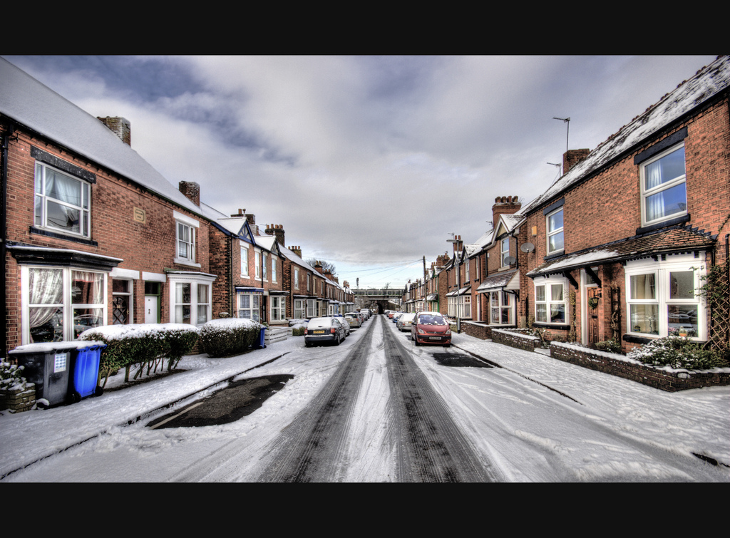 A road with terraced housing down either side, with some snow. Bare patches show ehere cars were when the slow fell