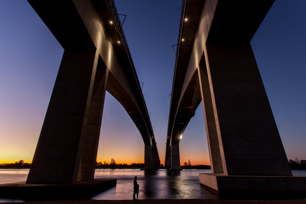 A young father and daughter dwarfed by the twin bridges.