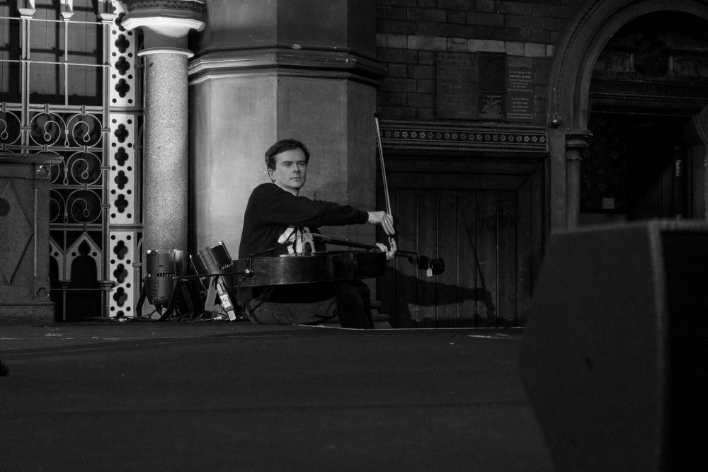 Cellist relaxing next to a stage.