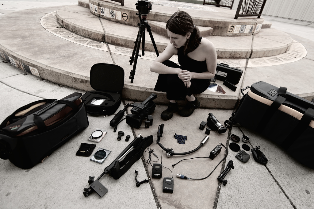 A woman surrounded by photographic equipment unpacked from her bag