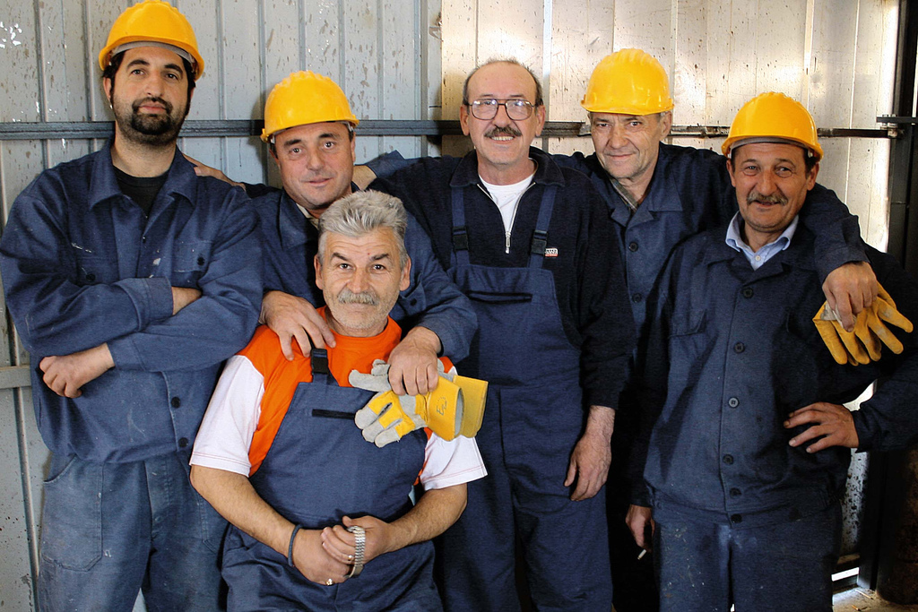 A group of men wearing hard hats and overalls pose for a group photo