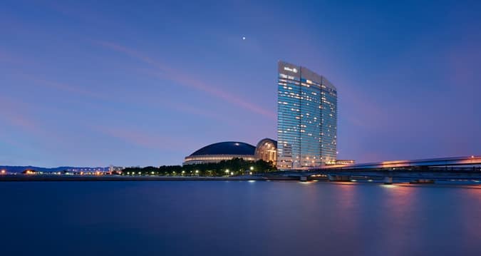 [Photo: twilight view of the Hilton Hotel form the water]