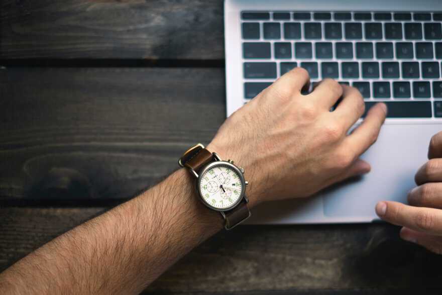 [illustration: top view of arm with wristwatch on a laptop keyboard]