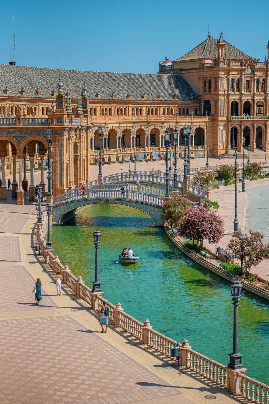 [Photo of the Plaza de España, with a canal, a bridge and part of the façade]