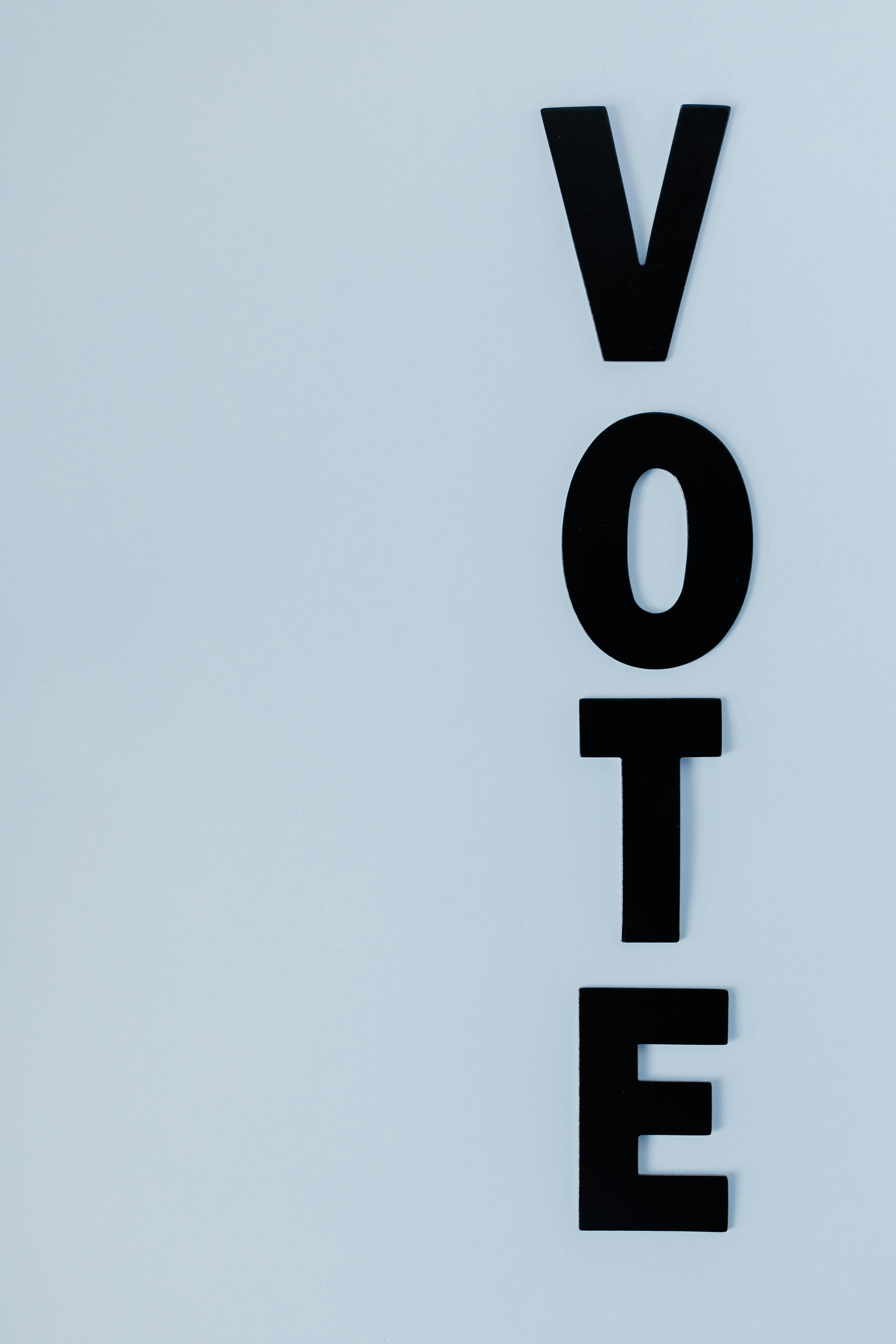 A paper cutout of the word Vote on a blue background.
