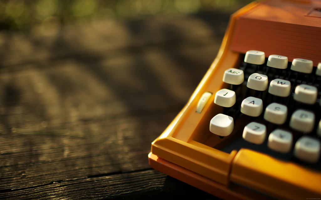 Orange typewriter on a wooden table close-up