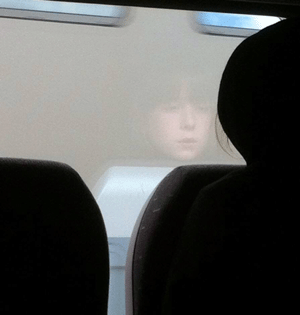 Reflection of a girls face in a train window.
