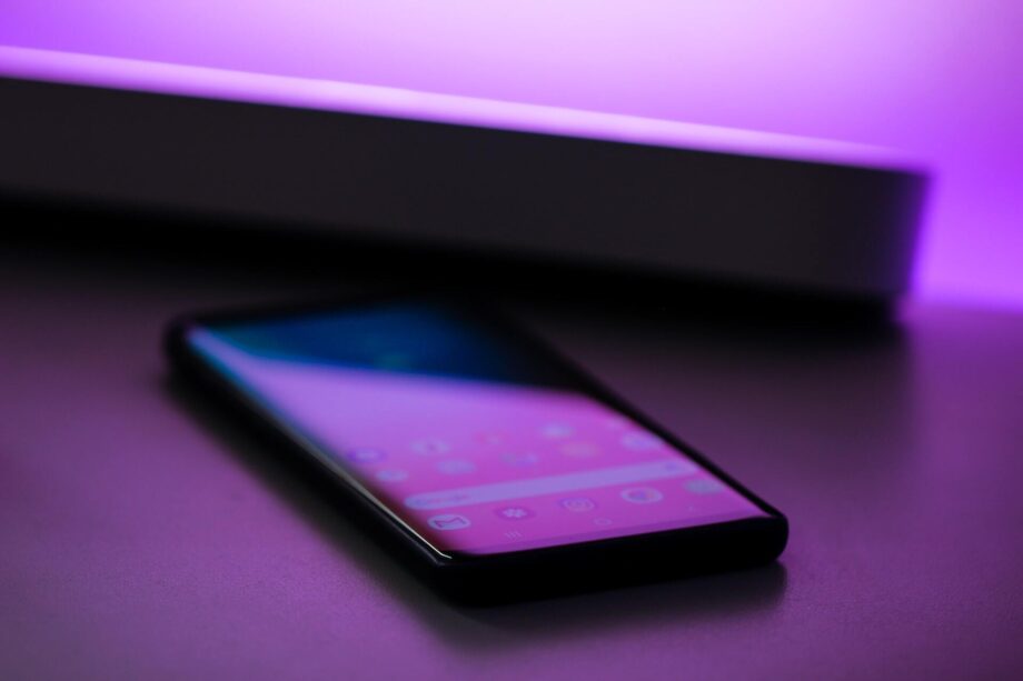 Smartphone on table in purple lighting. Photo by Jonah Pettrich on Unsplash