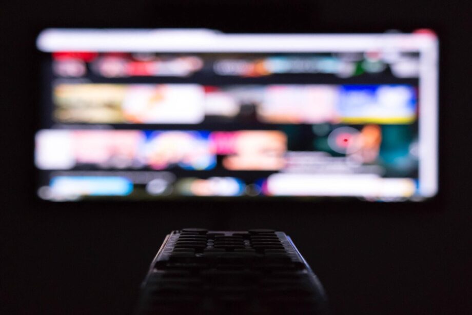 Blurry tv apps and remote control in the dark. Photo by Pinho on Unsplash