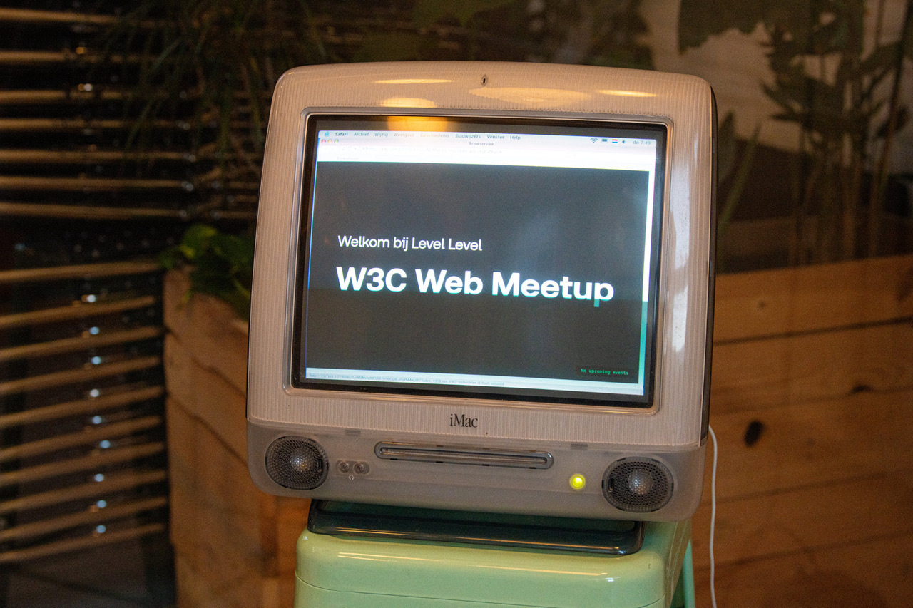 Vintage iMac running an old operating system displaying the text, in Dutch, 'welkom bij Level Level W3C Web Meetup'