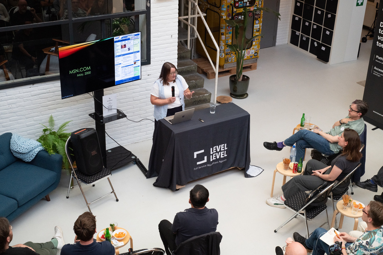 Cynthia photographed from above, speaking next to a screen that has a screenshot of MSN.com captioned MSN.com, May 2000.