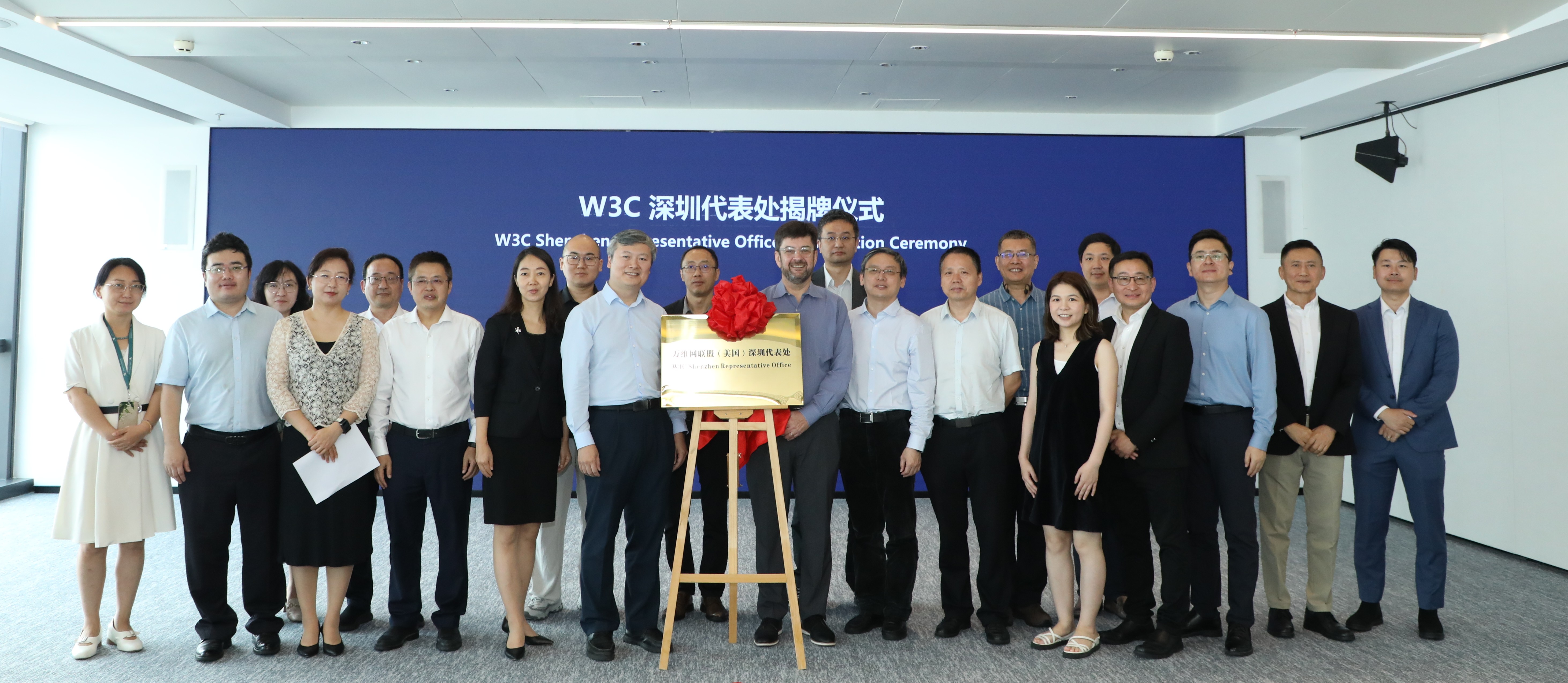 A group picture showing men and women posing on either side of an official opening plaque