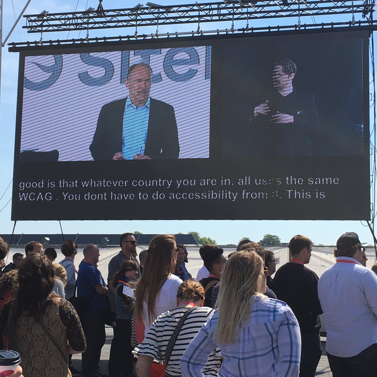 Tim Berners-Lee, text and a sign-language interpreter shown on a screen before an audience at SiteImprove